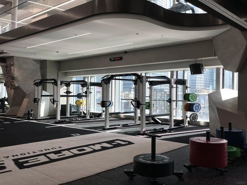 Installers laying down a large roll of padded turf in a gym construction site